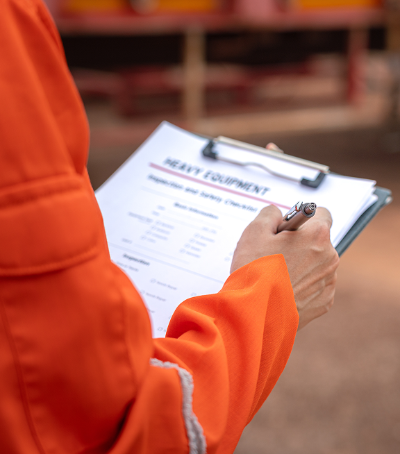 Worker in high-visibility uniform completing safety checklist on clipboard