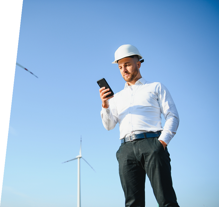 Field engineer with mobile device and wind turbine background